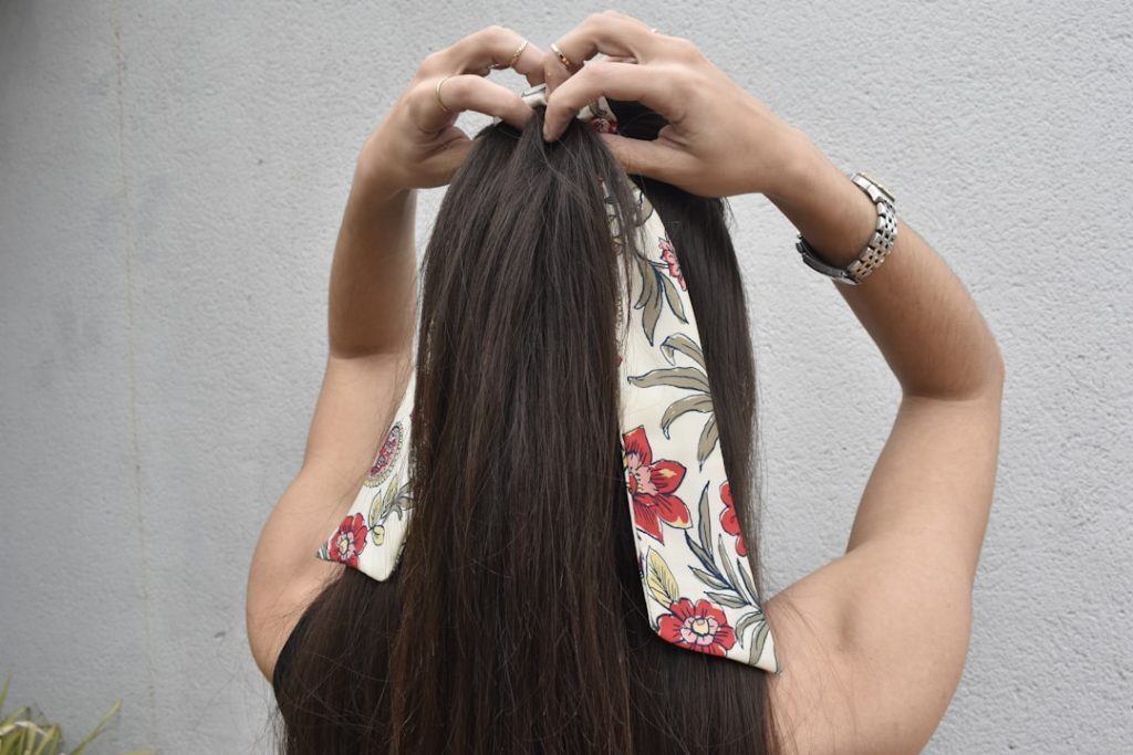 a-woman-with-long-hair-is-putting-on-a-bandana-uxwelm5jc8c