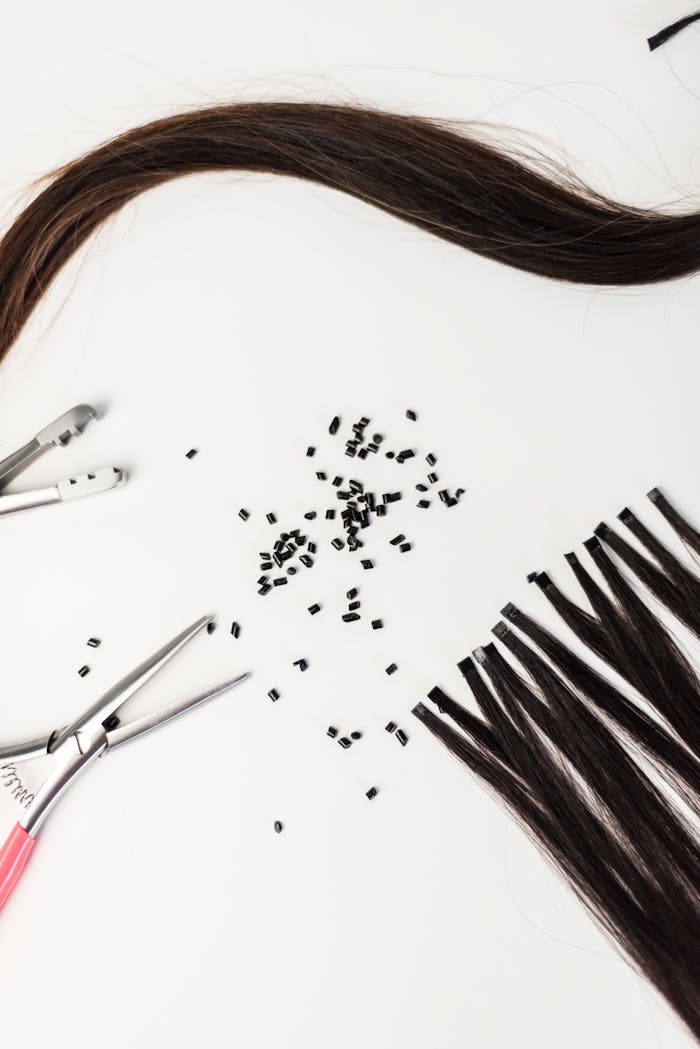 Close-up of hair extension tools and materials on a white background.
